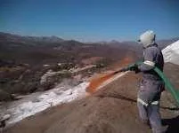 Técnico aplicando supresor de polvo con manguera sobre una superficie de jales